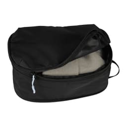 A black compression packing cube with a zippered opening, containing folded clothing inside.