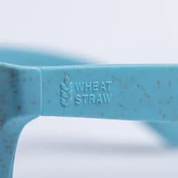 A close-up of a blue sunglasses frame featuring a texture with flecks and an embossed logo stating "Wheat Straw."