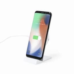 A smartphone with a partially charged battery sits on a white charging dock with a cable connected.