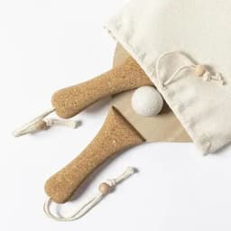 A cork paddle set with two paddles and a ball, neatly packed in a cream drawstring bag.