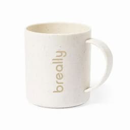 A cream-coloured mug with a speckled texture, featuring a handle and a branding logo.