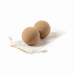 Two tan-coloured, spherical bath bombs resting on a natural fabric pouch. The pouch features a drawstring closure.
