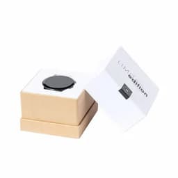 A black watch nestled in a light brown box, with an open lid revealing a white interior and branding.