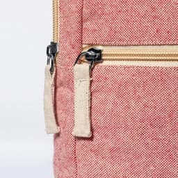 A close-up of a red fabric bag with a zipper, featuring a beige zip pull. The bag has a textured appearance.