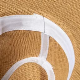 A close-up of a tan-coloured woven surface with a white fabric trim along the edges.