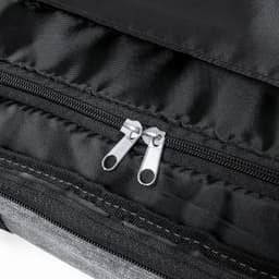A black and grey zipper detail on a fabric bag, showcasing twin silver zip pulls.