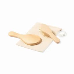 A wooden hairbrush and comb set displayed on a fabric pouch. The products are light-coloured with a natural finish.