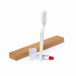 A dental kit featuring a white toothbrush, toothpaste, and a clear travel cap, all presented in a brown box.