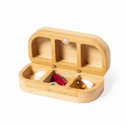 A bamboo pill organiser with three compartments and a small red, yellow, and white capsule inside. It has a logo.