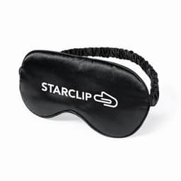 A black sleep mask featuring a logo, designed for comfort with an elastic band for a secure fit.