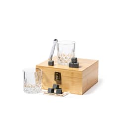 A wooden box with a clasp holds grey ice cubes beside two crystal glasses and a metal spoon.