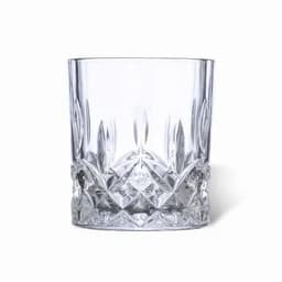 A clear crystal tumbler with a faceted design and a thick base, featuring decorative patterns.