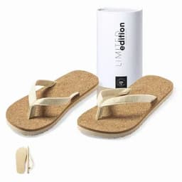 A pair of beige flip flops with a cork footbed, packaged in a sleek white box. The box features a logo.