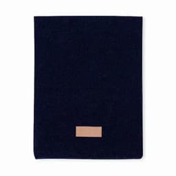 A navy blue fabric item with a tan leather patch, featuring a simple, minimalist design.