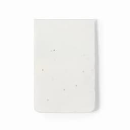 A white rectangular eraser with a smooth surface and rounded edges, featuring speckles throughout.