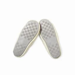 A pair of cream-coloured slip-on shoes with a checkered patterned sole. The shoes are lightweight and soft.