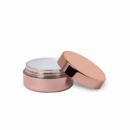 A round, rose gold container with a metallic lid, slightly open to reveal a white interior. It has a smooth finish and a logo.