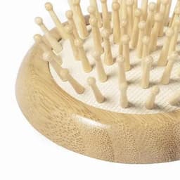 A wooden grooming board featuring multiple short pegs arranged in a circular pattern, set against a light background.