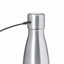 A drink bottle in shiny silver metal with a black cable attached to the top and a rounded lid.