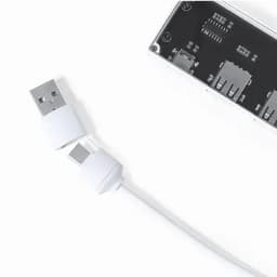 A USB charging cable in white connected to a rectangular device with multiple ports.