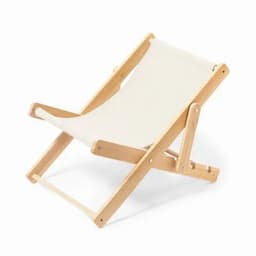 A deck chair with a natural wood frame and cream fabric seat, designed for relaxing outdoors.