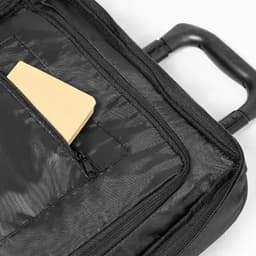 A black product bag featuring a zippered pocket partially open, revealing a yellow notebook inside.