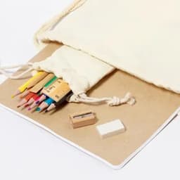 A drawstring pouch contains coloured pencils, a small sharpener, and an eraser, alongside a blank notebook.