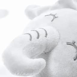 A plush elephant toy in soft white fabric with embroidered facial features and small details.