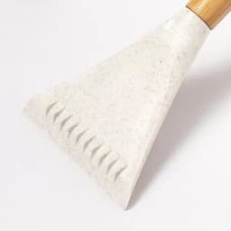A cooking spatula with a textured edge and a wooden handle, featuring a light grey and speckled design.