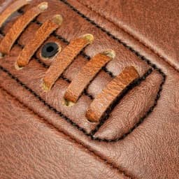 A close-up of brown leather with laces and stitching, showcasing its texture and detail.