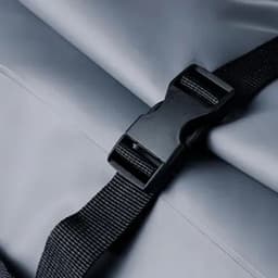 A drink bottle features a black buckle strap on a grey surface. The design includes a smooth, durable finish.