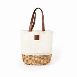 A cream tote bag with a woven wicker base and brown leather handles. It features a simple design and logo.