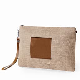 A clutch bag featuring a natural hessian exterior and a brown leather patch, with a detachable wrist strap.