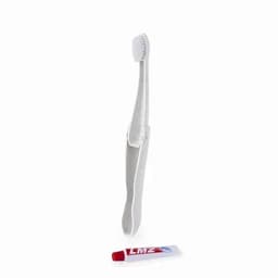 A toothbrush in white with a cap, positioned next to a red tube of toothpaste.