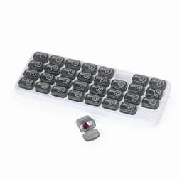 A grey and white pill organiser with compartments labelled for each day, featuring a small, red capsule beside it.