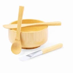 A bamboo bowl with two wooden utensils and a flat-edged tool, all in natural wood tones. The bowl has a smooth finish.