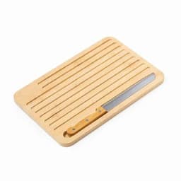 A wooden cutting board featuring grooves and a serrated knife with a wooden handle. The board is light-coloured.