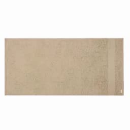 A bath towel in a soft beige hue, featuring a simple design and a small branding label on one side.