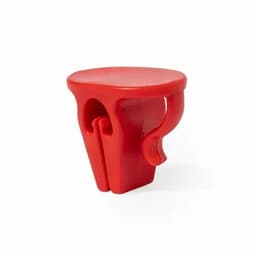 A red plastic product with a flat top and a curved handle, featuring two slots on the side. It has a simple design.