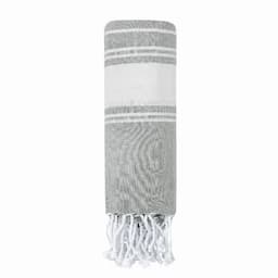 A rolled grey and white beach towel with fringed edges. The towel features alternating stripes.