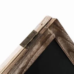 A wooden picture frame corner with a metal hinge, featuring a rustic finish and a black interior space.