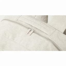 A backpack in a light cream colour featuring a zippered compartment and adjustable straps. It has a branding logo.