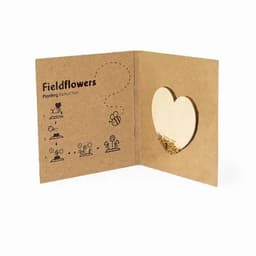 A seed planting card with a heart-shaped cutout and printed instructions, featuring illustrations of flowers and a bee.