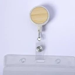 A badge reel with a wooden circular top and a clear plastic strap for securing identification or cards.