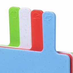 A set of chopping boards in blue, green, white, and red, with distinctive decorative handles. Each board features a logo.
