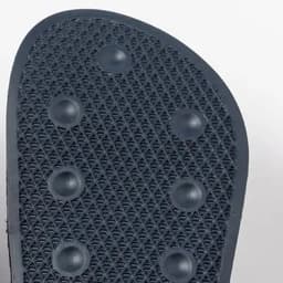 A black rubber shoe sole featuring a textured pattern and circular grips for traction.