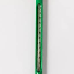 A thermometer with a green casing, featuring a clear glass tube filled with liquid and a scale marked in Celsius.