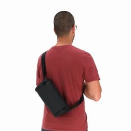 A black drink bottle with a strap, held by a person wearing a red shirt. The person is facing away from the camera.