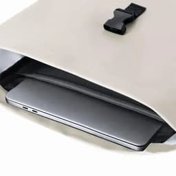 A light-coloured backpack with a sleek laptop compartment visible inside. The bag features a simple clasp closure.