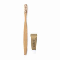 A bamboo toothbrush with a textured handle and a small tube of toothpaste in a gold wrapper.